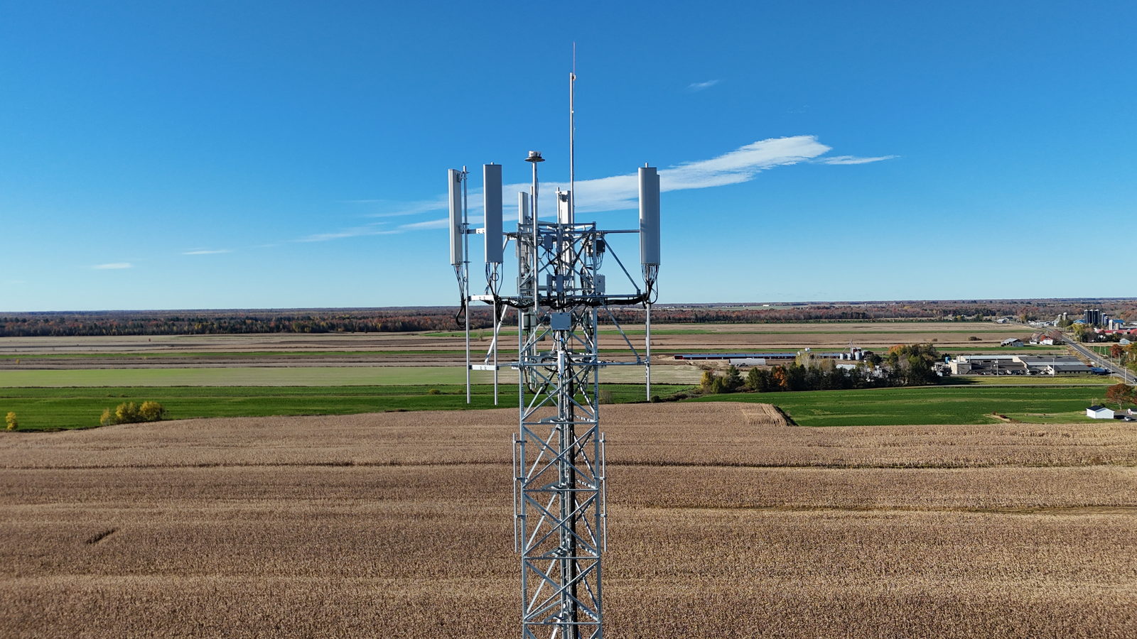 Pylône de télécommunications équipé d'antennes au-dessus d'un champ, vu du ciel